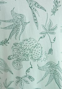 Tela verde claro con intrincadas ilustraciones botánicas en verde oscuro, que incluyen cactus, hojas y flores de diversas formas.