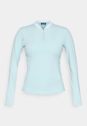 T-shirt de manga longa azul claro com um colarinho alto, fecho de zip na frente e detalhes em painéis laterais. Feito de um tecido suave e elástico.