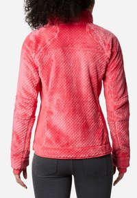 Giacca in pile di un vivace colore rosa con motivo lavorato sul retro, caratterizzata da un colletto alto e maniche lisce a contrasto.
