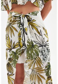 Witte wikkelrok met groene en zwarte tropische bladerenprints. Geknoopt in de taille, met een hoge split voor een soepel design.