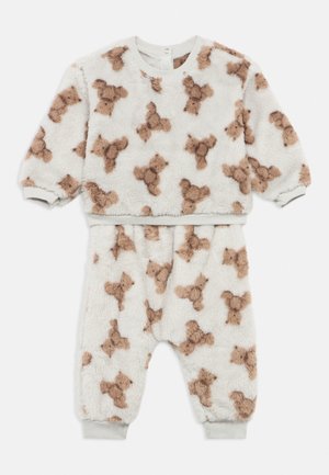 Zacht wit peuterfleece-setje met bruin teddybeertjespatroon, lange mouwen, elastische manchetten en bijpassende broek met enkelboorden.