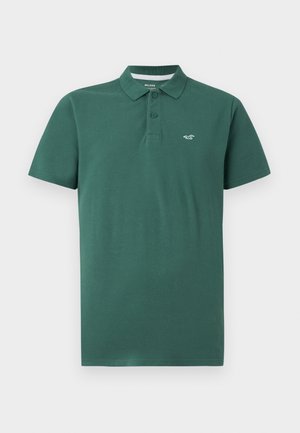 Polo verde in cotone, con colletto classico, due bottoni e un piccolo logo sul lato sinistro. Maniche corte e vestibilità standard.