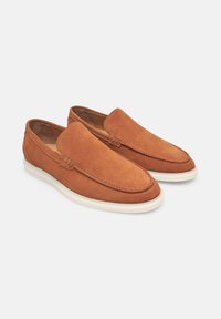 Mocassini in suede marrone con una texture liscia, design slip-on, punta arrotondata e suola in gomma bianca a contrasto.