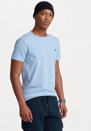 Tricou din bumbac de culoare bleu deschis, cu mâneci scurte și guler rotund, având un mic logo brodat pe piept. Purtați cu pantaloni bleumarin.