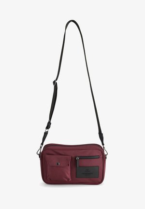Lille rektangulær crossbody-taske i mørkerød med to forlommer, en med lynlås og en med trykknap, samt en justerbar sort rem.