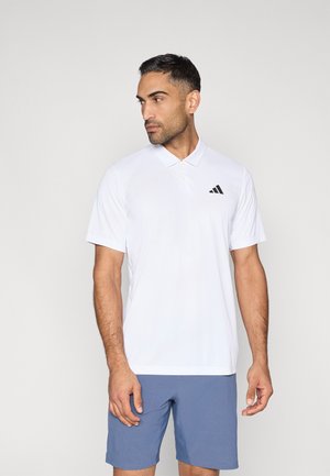 Hvid polo med krave, korte ærmer og et sort Adidas-logo på venstre bryst. Stoffet virker glat og let.