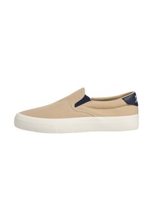 Beiger Slip-On Canvas-Sneaker mit weißer Sohle und marineblauen elastischen Seitenteilen und Fersenlasche.