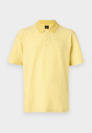 Yellow polo shirt made of cotton, featuring a buttoned collar, short sleeves, and a subtle embroidered logo on the chest.