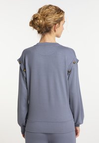 Grijze sweatshirt met lange mouwen en een ronde halslijn, gatherende mouwen en decoratieve knopen op de schouders. Gladde, zachte stof.