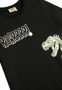 Schwarzes Baumwoll-T-Shirt für Kinder mit dem Text "ROARRRR!" in Weiß und einem grünen Dinosaurier-Schädel-Graphic auf der Vorderseite.