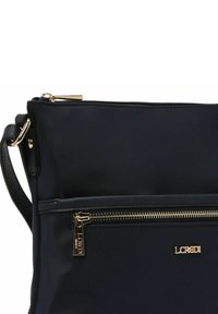 Borsa a tracolla nera in nylon con hardware dorato, apertura con zip e tasca frontale con design a strisce testurizzate.
