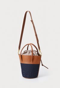 Brown leather and blue denim bucket bag with a clasp and adjustable strap, featuring a patterned fabric interior and embossed detail on denim.