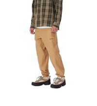 Los joggers de felpa color beige presentan un corte relajado, costuras visibles y un logo amarillo. Se combinan con una camisa de cuadros y zapatos resistentes.