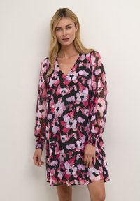Blumenmusterkleid mit V-Ausschnitt, langen durchsichtigen Ärmeln und gerafften Manschetten. Die Farben umfassen Rosa, Lila und Schwarz auf einem leichten Stoff.