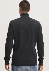 Pulover tricotat de culoare gri închis, cu guler înalt, având dungi texturate orizontale. Mâneci lungi și manșete cu nervuri completează designul.