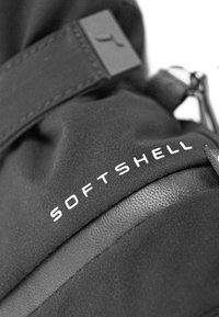 Schwarzes Softshell-Material mit glatter Textur, ausgestattet mit einem auffälligen "SOFTSHELL"-Etikett und einem eleganten, minimalistischen Design.