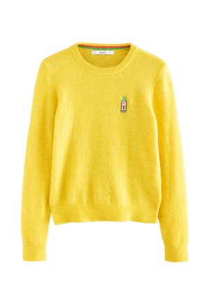 Világos sárga környakas pulóver hosszú ujjakkal és egy kis zöld hímzett palackfolttal a bal mellrészen.