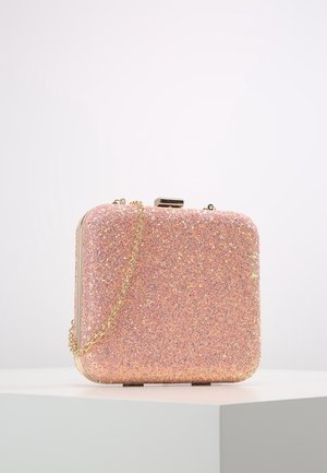 Lille firkantet pink glitrende clutch taske med guldkæde, placeret på hvid piedestal mod ens hvid baggrund.