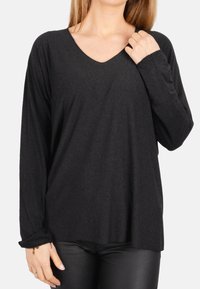 Schwarzes Langarm-T-Shirt mit V-Ausschnitt, aus weichem Material, mit einer lockeren Passform und gerippten Ärmelbündchen.