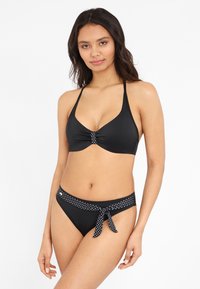 Zwarte bikini met een haltertop met een gerimpeld midden en een broekje met een stippenriem en strikdetail. Soepele stofstructuur.