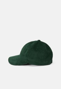 Gorra de béisbol de pana verde con visera curva, rayas verticales texturizadas y seis ojales de ventilación. Diseño simple y estructurado.