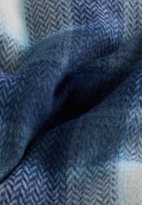 Gyapjú takaró, herringbone mintával, különböző kék és világoskék árnyalatokban. Textúrája puha, és meleg, otthonos megjelenésű.