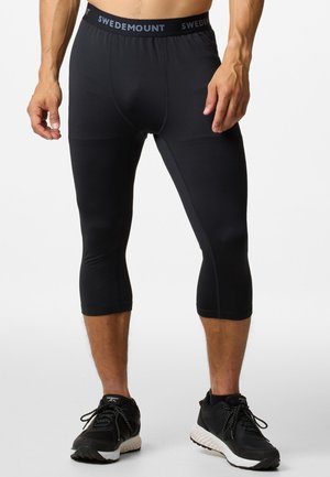 Black athletic capri pants made of stretchy fabric, featuring a branded waistband and a form-fitting design, cut just below the knee.