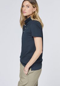 Marinefarbendes Poloshirt mit kurzen Ärmeln, einem Button-Down-Kragen und einer figurschmeichelnden Passform. Aus weicher Baumwolle gefertigt, mit einem dezenten Logodetail.