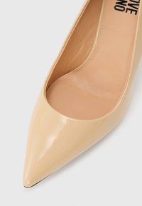 Μπεζ ψηλοτάκουνο γυναικείο παπούτσι από δέρμα με λείο φινίρισμα και εμφανή ραφή στην εσωτερική σόλα.
