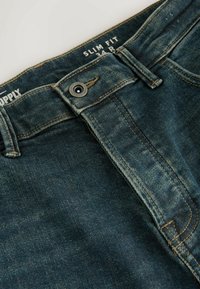 Smal pasform denimjeans i mørkeblå med en subtil slidt tekstur. Har metalknaplukning, fem-lomme stil og kontrasterende syninger.