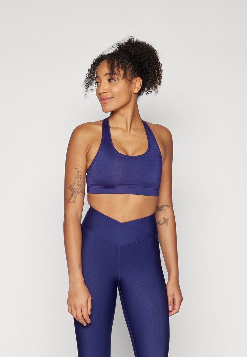 Mørkeblå sports-BH med tykke stropper, sømløst design og bredt underbånd. Kombinert med matchende høytalende leggings med V-formet liv.