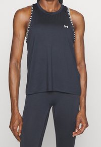 Top deportivo negro sin mangas con escote redondo, diseño de espalda nadadora y tirantes con marca, confeccionado en una tela suave y liger. 