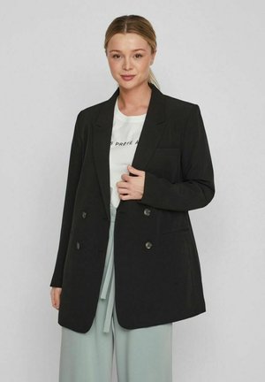 Blazer nero doppiopetto con rever a punta, due tasche frontali e bottoni metallici lucidi. Tessuto liscio, vestibilità strutturata.