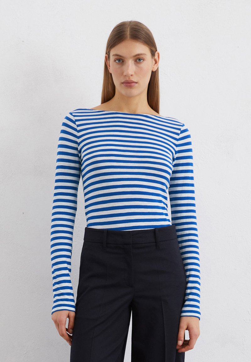 Blue and white striped long-sleeve top made of soft fabric, featuring a boat neckline and fitted silhouette, paired with tailored black pants.