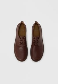 Καφέ δερμάτινα παπούτσια με λείο φινίρισμα, στρογγυλή μύτη και παραδοσιακό σχέδιο με κορδόνια. Στο εσωτερικό διαθέτουν ταμπά πάτο και ελάχιστη σήμανση.