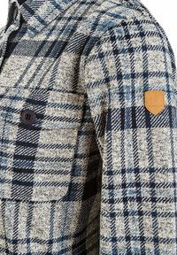 Ruitjesjas in beige, marineblauw en lichtblauw. Gemaakt van een gestructureerde stof met een borstzak en leren logo op het mouw.