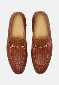 Smeđi tkanih kožnih loafers s detaljem od zlatnog konjića sprijeda. Glatka unutarnja obloga i strukturirana potplata.