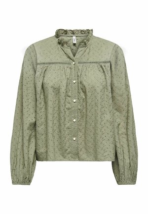 Blouse à manches longues vert clair avec broderie ajourée, col à volants, boutons-pression sur le devant et poignets élastiqués sur les manches.
