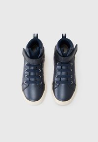 Marine høye sneakers med teksturerte sorte stoffpaneler, hvite gummisåler og metalløyer, med en krok-og-løkke stropp for sikker passform.