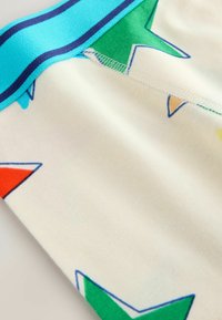 Kolorowy, miękki materiał o jasnobeżowej podstawie z wielokolorowymi gwiazdkami w odcieniach czerwieni, zieleni i żółci. Niebieski pas dodaje kontrastu.