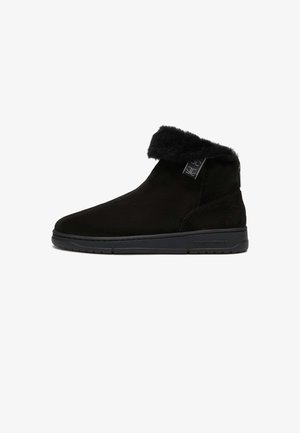 Black suede ankle boot with folded fur cuff, side tag, and flat rubber sole, designed for cold weather.