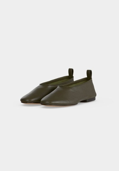 Paire de ballerines en cuir souple vert olive avec bouts arrondis et languettes au talon, sur fond blanc uni.