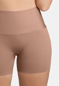Beige naadloze shapewear shorts met een hoge taille, gemaakt van gladde, rekbare stof. Heeft een strakke snit zonder zichtbare naden.