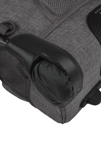 Graue Reisetasche mit strukturierter Oberfläche, Hartplastikgriff, integrierten Reißverschlüssen und einem Netzfach. Ein gerollter Stoffabschnitt ist sichtbar.