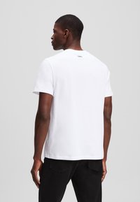 Witte korte mouwen t-shirt met een ronde hals, voorzien van een klein logo op het achterste gedeelte van de nek. Zachte katoenstof, relaxed fit.