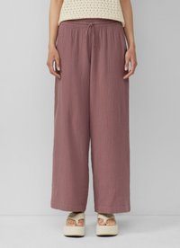 Pantalons larges à coupe décontractée en mauve, en tissu texturé, avec une taille élastique et un cordon de serrage. Associés à des sandales compensées.