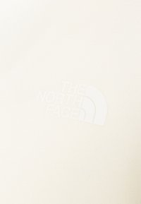 Tessuto bianco con un logo in rilievo sottile del marchio "The North Face" sulla superficie.