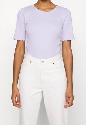 Lawendowy prążkowany top z krótkimi, falbaniastymi rękawami, zestawiony z białymi, wysokim stanem dżinsami. Prosty, dopasowany fason z okrągłym dekoltem.