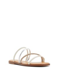 Płaskie sandały z trzema paskami: dwa białe i jeden pleciony w kolorze tan. Wyposażone w srebrny okrągły akcent. Naturalna kolorystyka podeszwy zapewnia komfort.