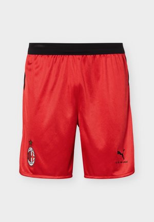 Rode voetbalshorts met zwarte elastische tailleband, AC Milan-logo op linkerpijp, Puma-logo en “Slam Jam” tekst op rechterpijp.